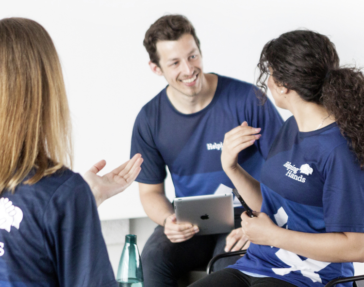 Drei Personen mit Helping-Hand-Shirts inmitten eines Gesprächs