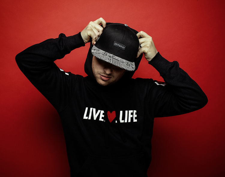Foto des Rappers Stunnah mit Live.Heart.Life Hoodie vor rotem Hintergrund